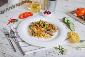 Pasta with olive meat greens on a white plate