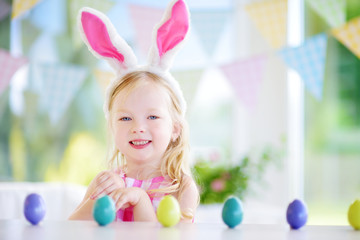 Cute little girl wearing bunny ears playing egg hunt on Easter