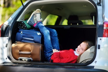 Adorable little girl ready to go on vacations with her parents. Kid relaxing in a car before a road trip.