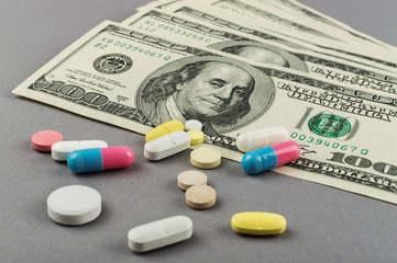 A lot of pills and money on the grey background