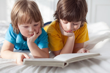 two boy read book indoors