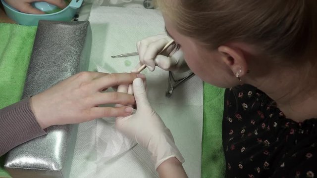 Blonde manicure master cuts the cuticula