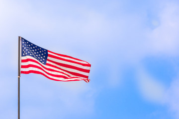 American flag waving under the blue sky and clouds