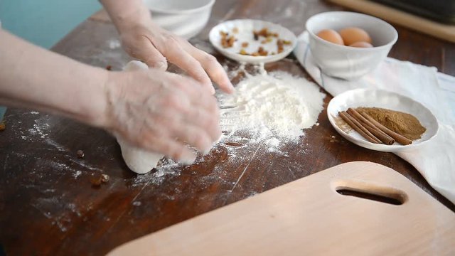 A man prepares a dough for baking buns and apple pie.