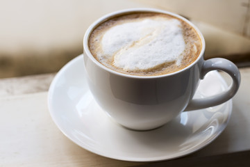 Hot coffee in a white cup is at the window.