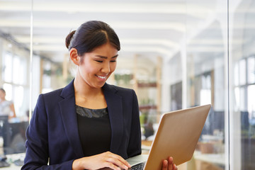 Asiatische Frau schaut auf Tablet Computer