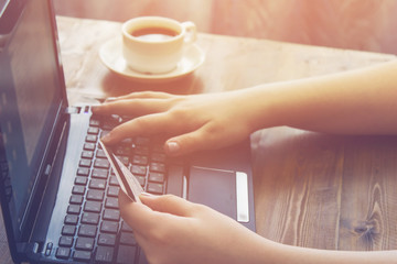 Woman holding credit card sitting in front of laptop. vintage effect