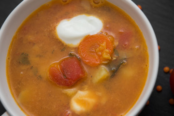 close up on soup with tomato, lentil and potato, rustical background, top view