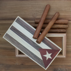 Studio scene of Cuban cigars and vintage cigar box on old wooden table.
