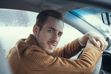 young boy smiling while sitting behind the wheel