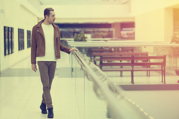a young guy in a beige jacket walking through the Mall