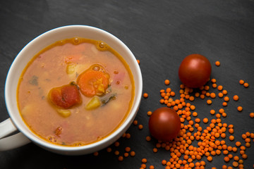 close up on soup with tomato, lentil and potato, rustical background, top view