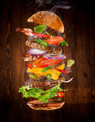 Big tasty burger with flying ingredients.