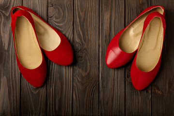 Red women's shoes (ballerinas) on wooden background.