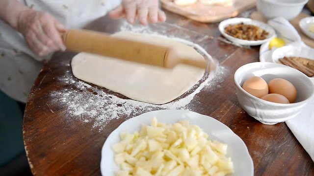A man prepares a dough for baking buns and apple pie.