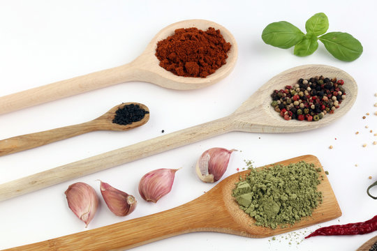 Various herbs and spices in wooden spoons. Flat lay of spices ingredients chilli ,pepper, garlic,dries thyme, nutmeg,rosemary, sweet basil and matcha on white background