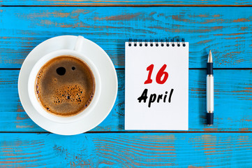 April 16th. Day 16 of month, loose-leaf calendar with morning coffee cup, at workplace. Spring...