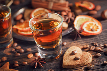Whiskey or liqueur, cookies, spices and decorations on wooden background.