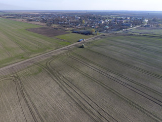 Fototapeta premium Tractor with hinged system of spraying pesticides. Fertilizing with a tractor, in the form of an aerosol, on the field of winter wheat.