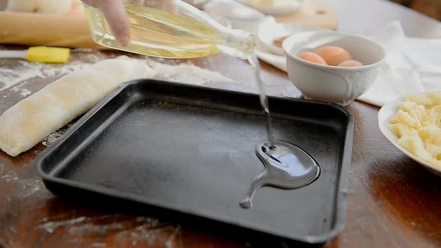 Grease the baking tray with oil. The chef lubricates the pan with a brush and oil before baking the dessert.