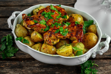 New boiled potatoes with dill and butter served with baked skinless boneless chicken thighs in vintage casserole