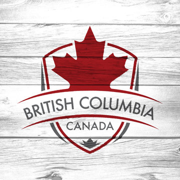 A Canadian province crest on a background of distressed barnboard. The shield features a maple leaf and the main text says British Columbia, Canada.