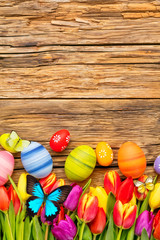 Easter eggs with tulips and butterfly on wooden board