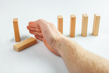 Hand stopping dominoes falling isolated on white background