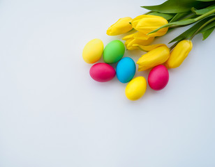 Easter eggs with yellow tulips on white background, copy space for text