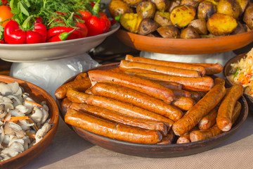 Grilled sausages on  plate, fried potatoes and red pepper on the table