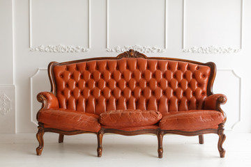 Vintage leather sofa on a wooden floor white stucco on a white background