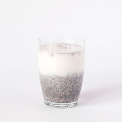 Chia pudding with chia seeds and milk in a glass on white background.