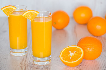 Fototapeta na wymiar orange juice in glasses at light wooden background