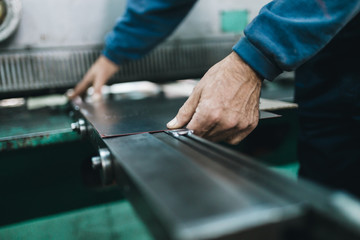 Metallurgy heavy industry. Factory for production of heavy pellet stoves and boilers. Worker hands close up. Extremely dark conditions and visible noise. Focus on foreground.