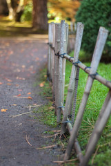 old bamboo fence off pathway with green grass and fallen leaves