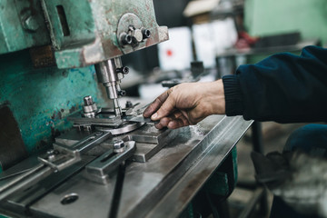 Metallurgy heavy industry. Factory for production of heavy pellet stoves and boilers. Worker hands close up. Extremely dark conditions and visible noise. Focus on foreground.