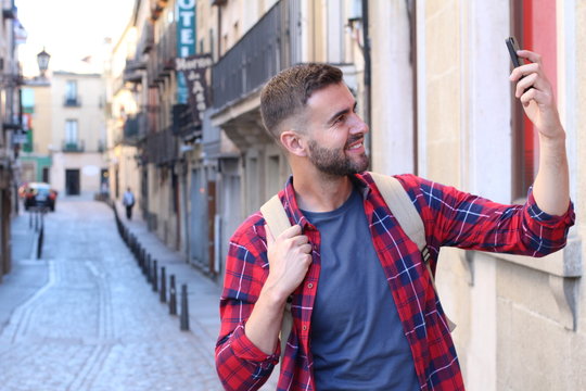 Man taking a selfie while walking around a fancy city street 