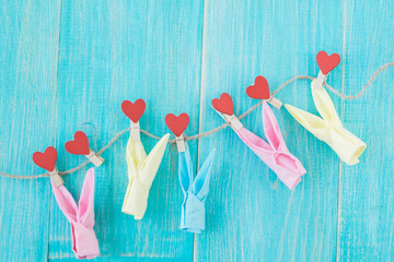 Clothespins with hearts on rough rope and blue vintage wooden background. Concept of love.