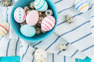 Colorful Easter Eggs on the rustic wooden background in blue bowl and linens towel. Selective focus.