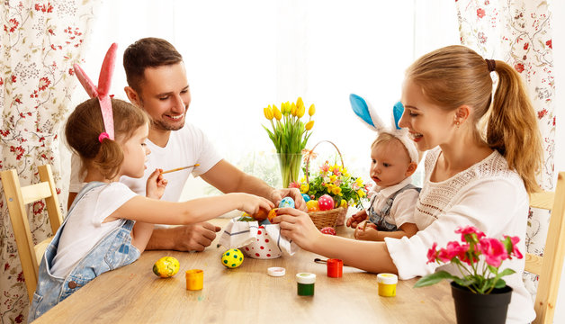 Happy easter! family mother, father and children paint  eggs for holiday.