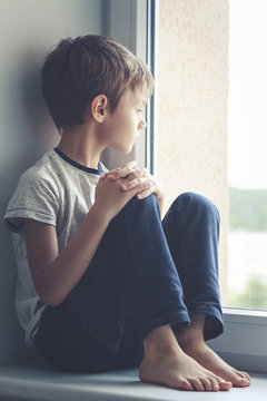 Sad Child Sitting On Window Shield And Looking Out The Window