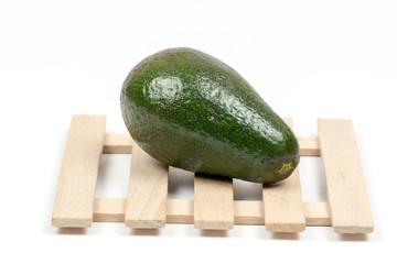 Whole green avocado on the wooden background