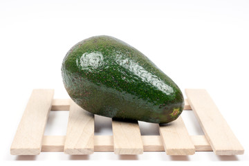 Whole green avocado on the wooden background