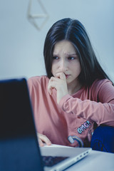 sad and scared female teenager with computer laptop suffering cyberbullying and harassment being...