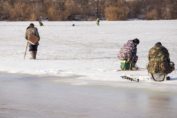  Fishermen on the river catch fish on thin ice in the spring. The danger of falling under the ice. Near the water from melted ice