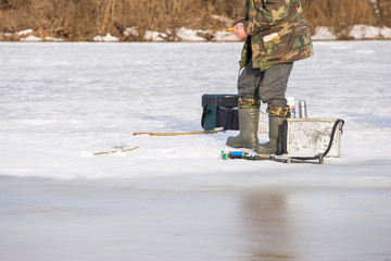  Fishermen on the river catch fish on thin ice in the spring. The danger of falling under the ice. Near the water from melted ice