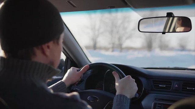 Young man driving car on the winter road.