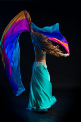 Portrait of a young girl with long hair in a turquoise costume oriental dancer with a multicolored...