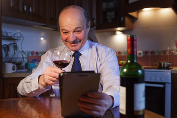 An elderly man with a mustache in a shirt and tie congratulates friends or relatives on a solemn event. Communication in the distance, video chat via the Internet.