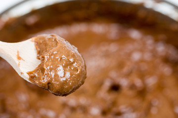 Chocolate cocoa brown cream on the wooden spoon with blurred background